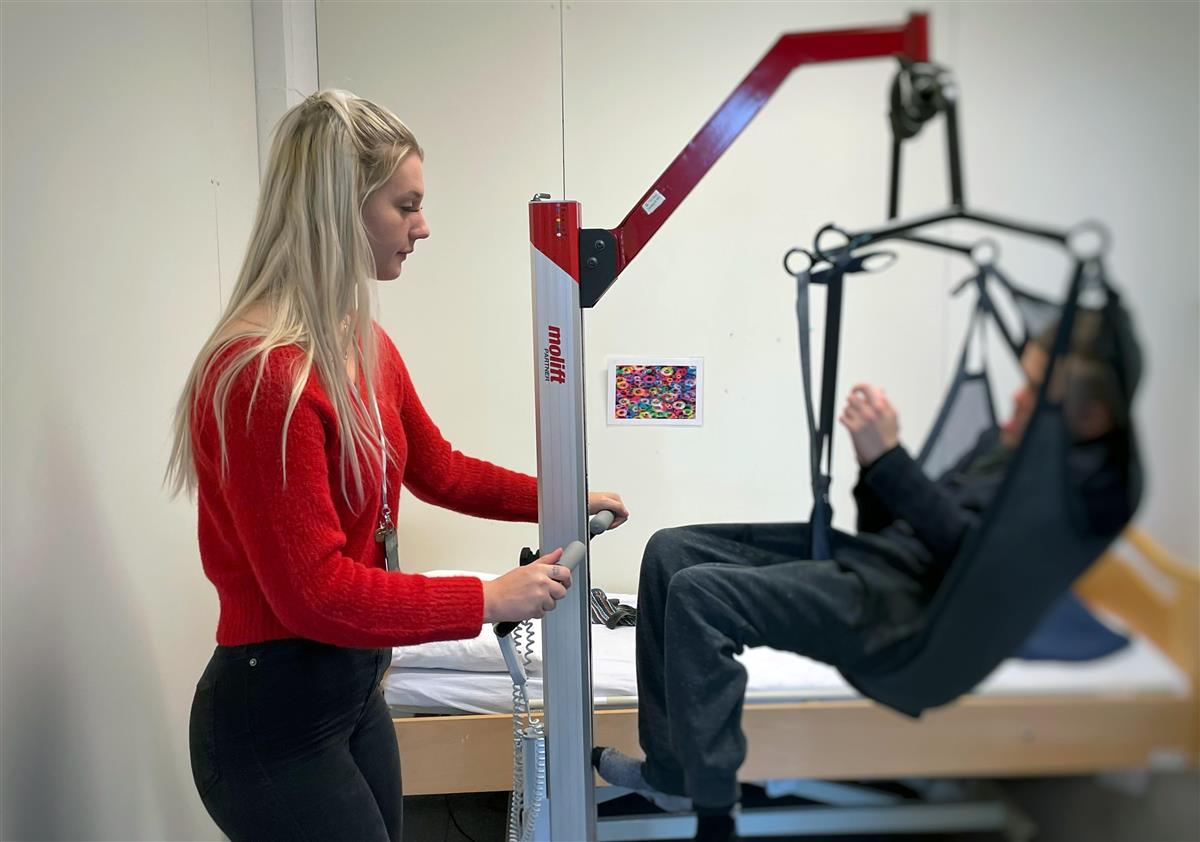 helsearbeider bruker løfteutstyr for å løfte funksjonshemmet gutt - Klikk for stort bilde