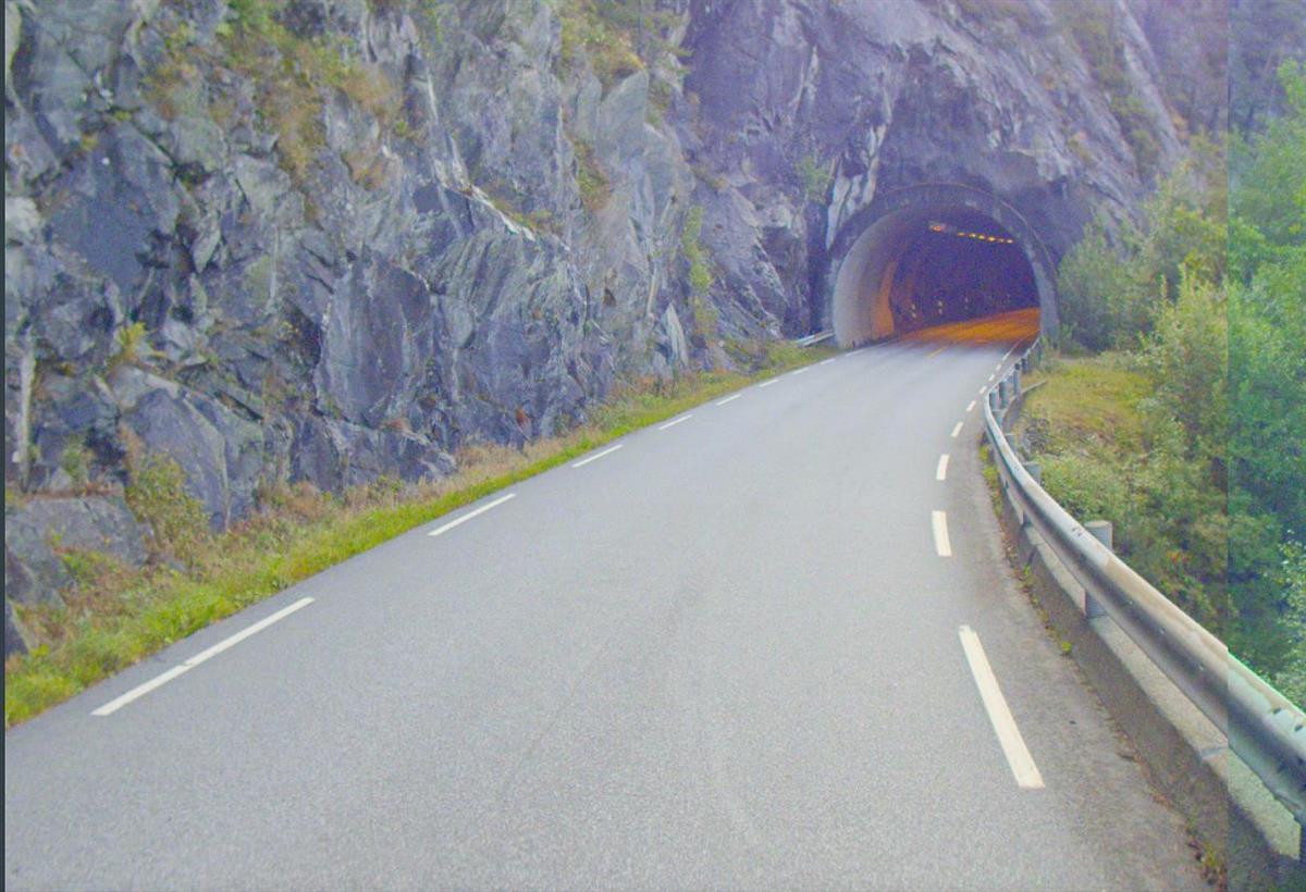 en vei som går inn i en tunnelåpning med en fjellside på venstre side. - Klikk for stort bilde