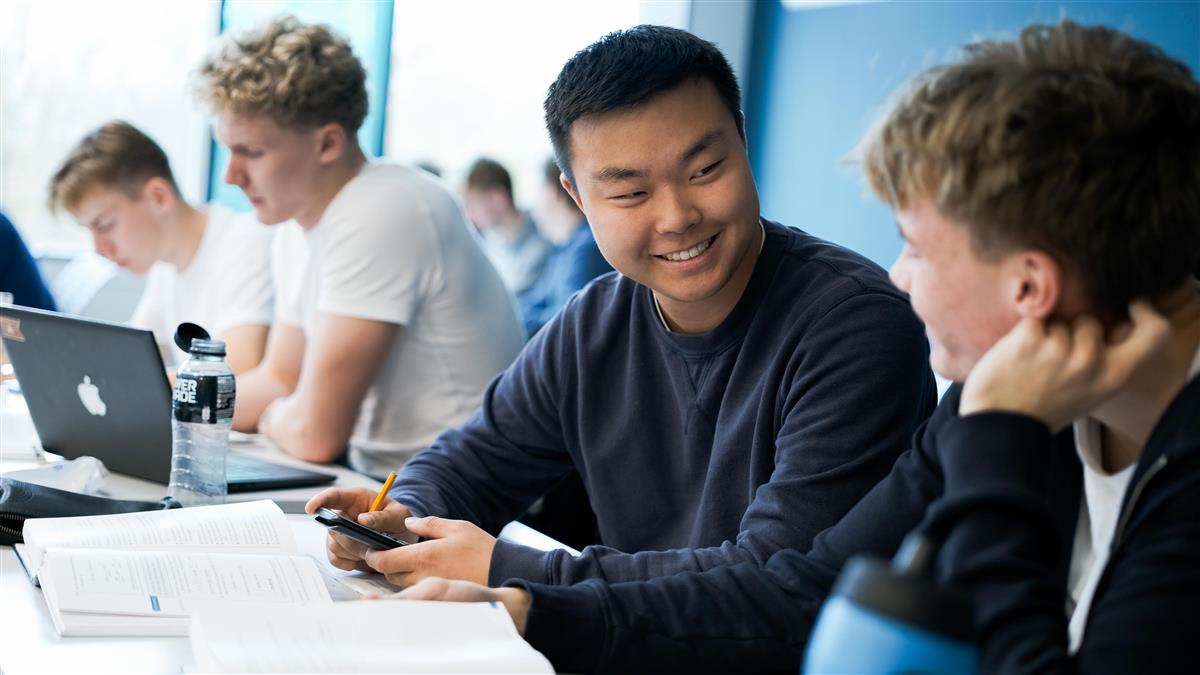 To elever snakker sammen i klasserom - Klikk for stort bilde