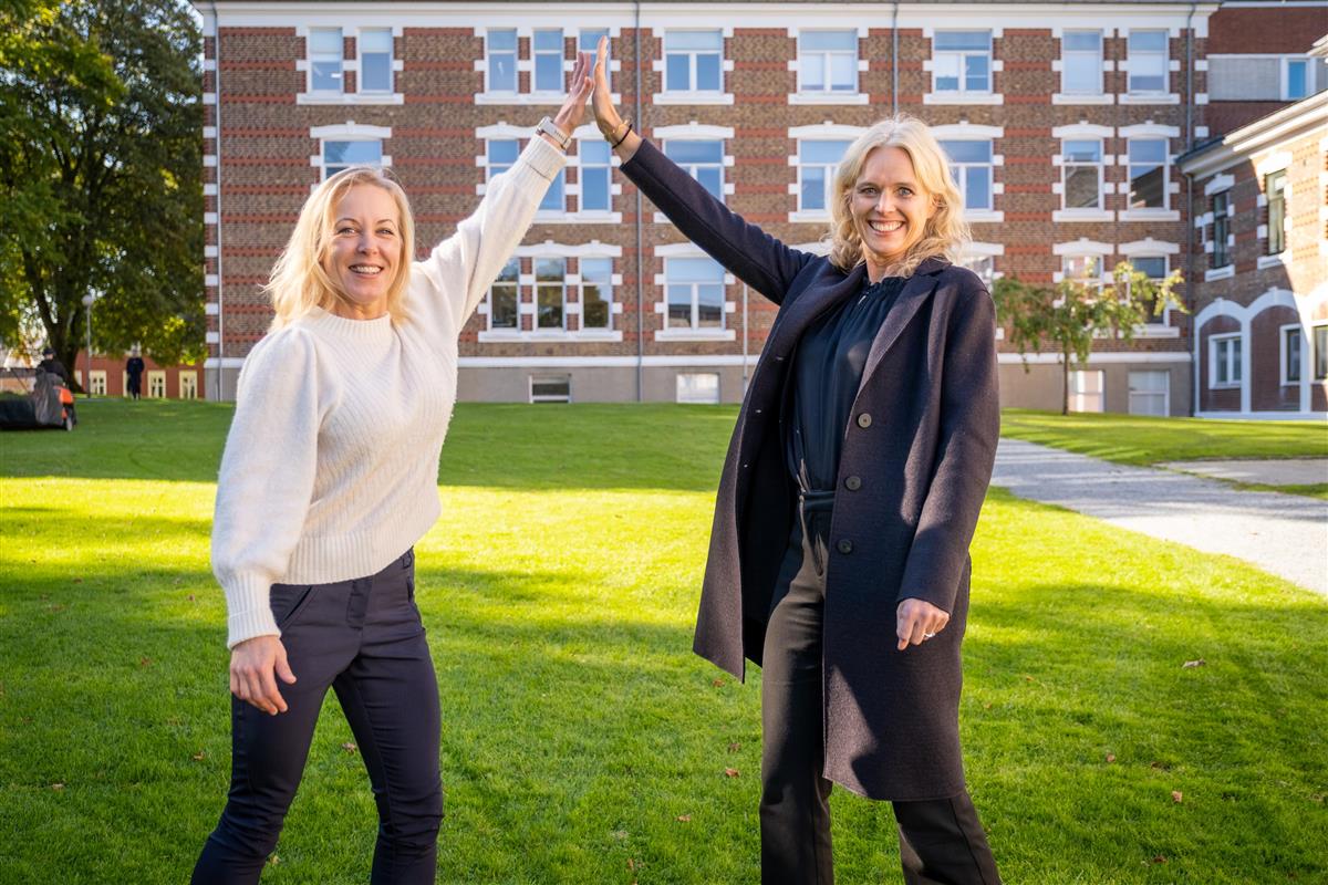 To damer gir high five i en park - Klikk for stort bilde