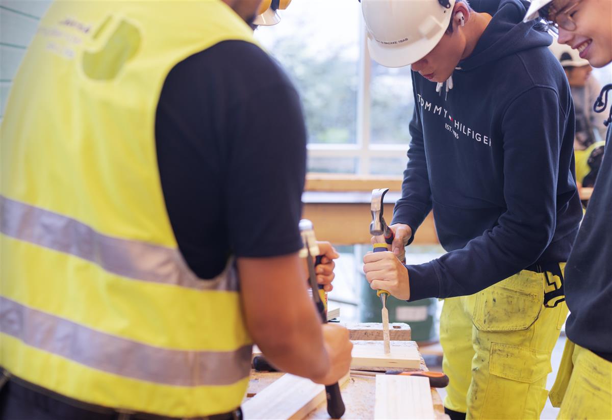 Menn i gul vest hamrer spiker. Foto - Klikk for stort bilde