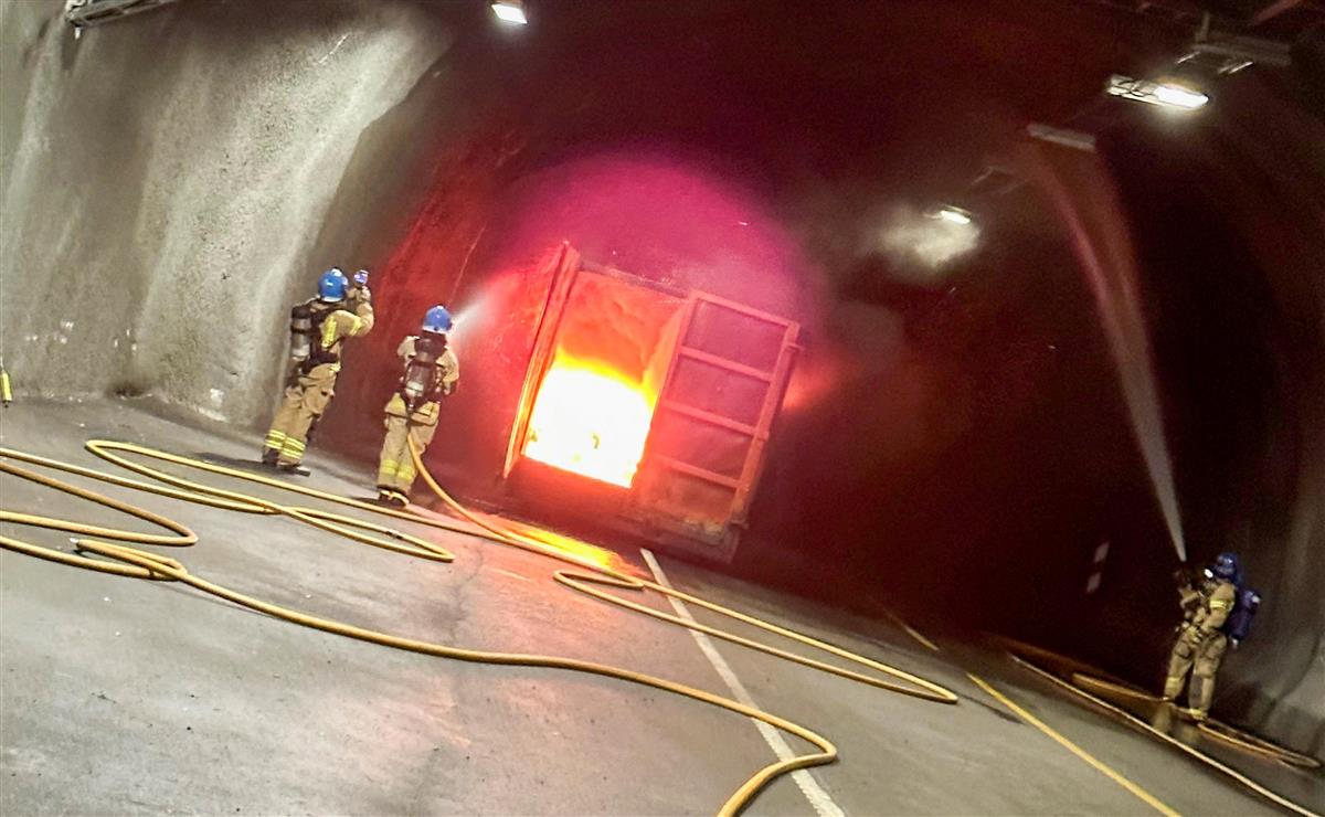 Tre brannmenn slukker en brann i en container i tunnel - Klikk for stort bilde
