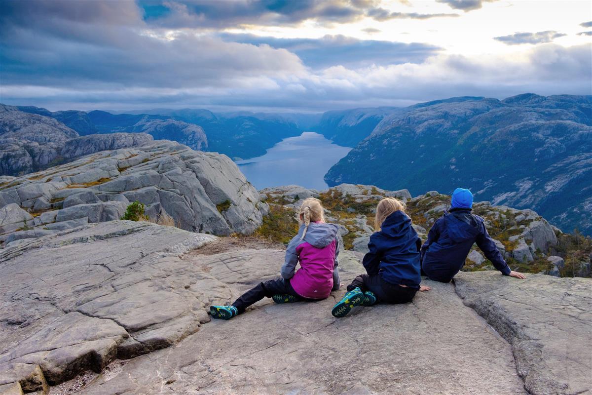 Tre barn på toppen av Preikestolen kikker utover Lysefjorden. - Klikk for stort bilde